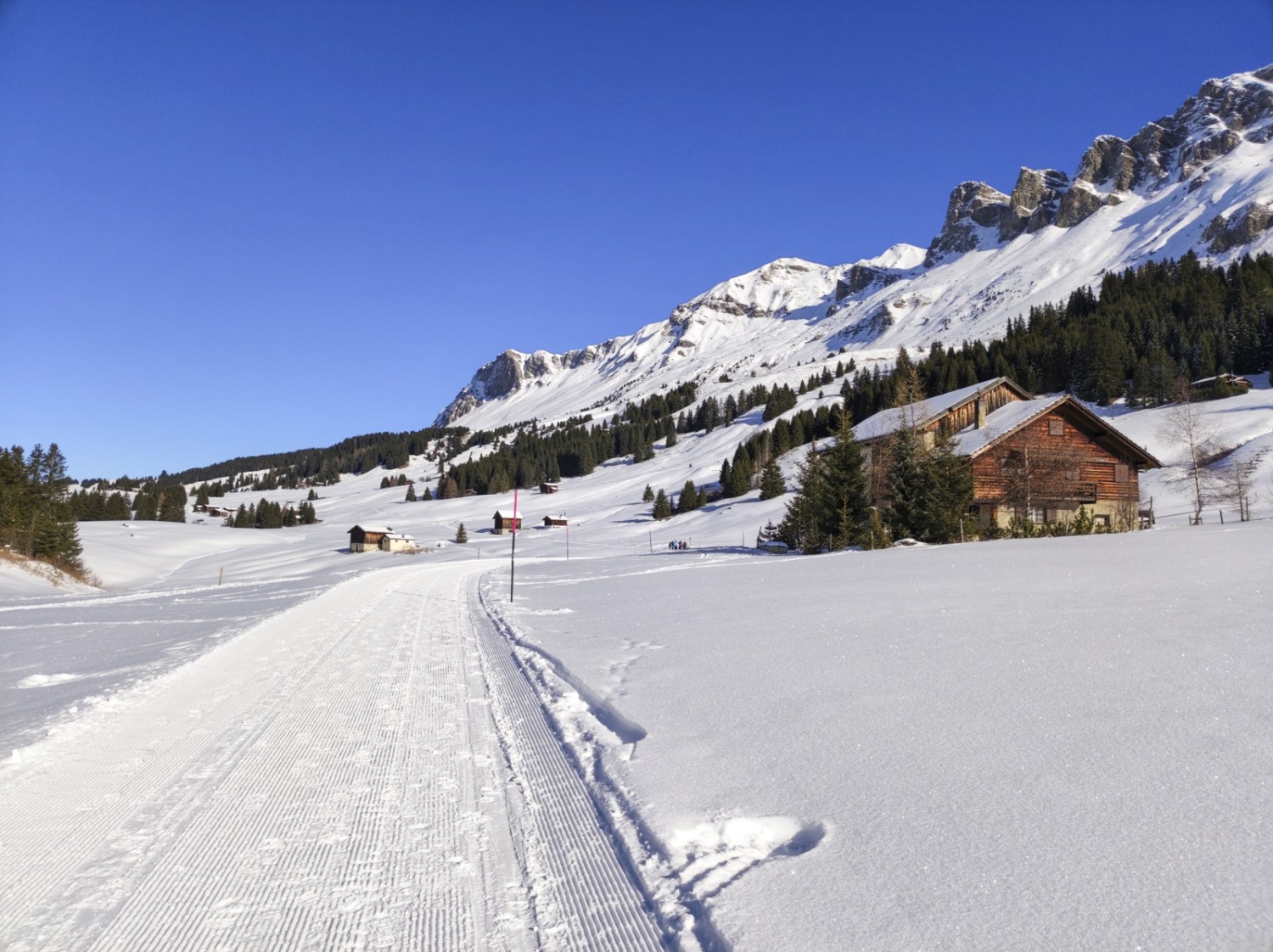 Zwischen vereinzelten Häusern schlängelt sich der Weg über das kleine Plateau. Bild: Michael Dubach